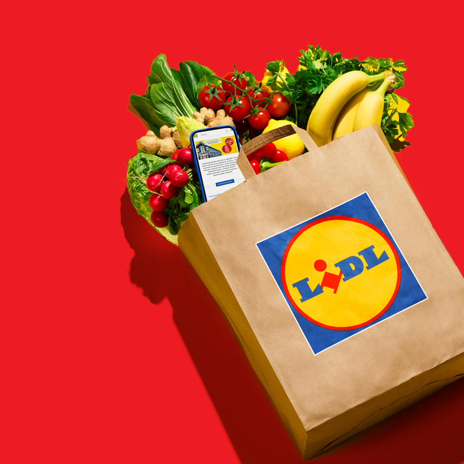 Papirnata vrećica s logotipom Lidla, puna svježeg voća i povrća, s telefonom unutra.