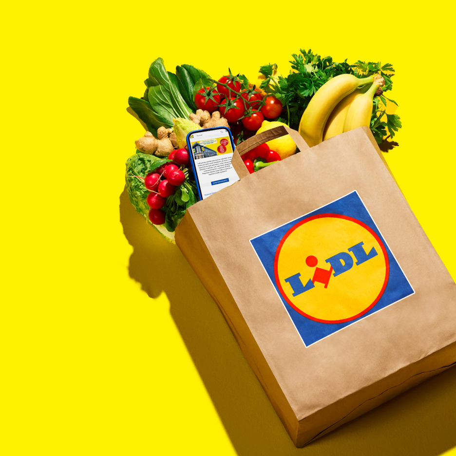 Smeđa papirnata vrećica s logotipom Lidla, puna svježeg povrća i voća, sa pametnim telefonom.