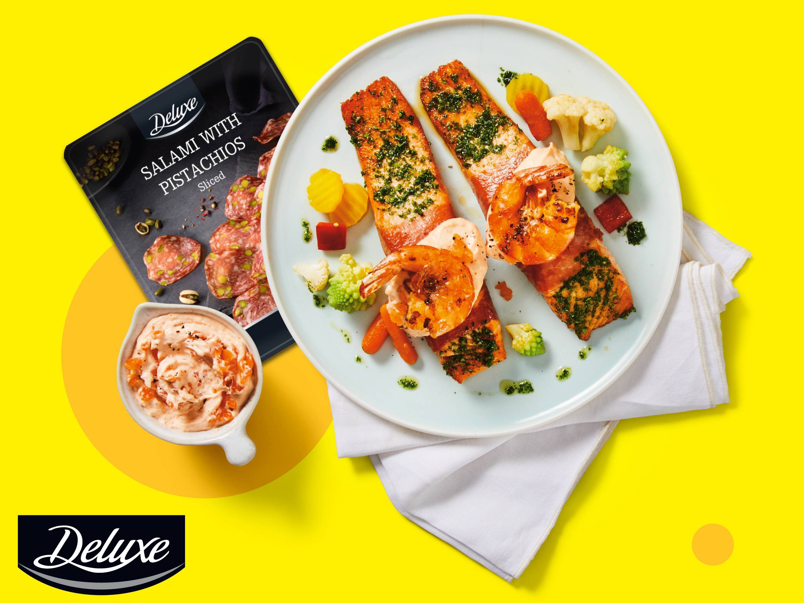 Pakiranje salame s pistacijama, umak i tanjur s lososom, kozicama i povrćem.