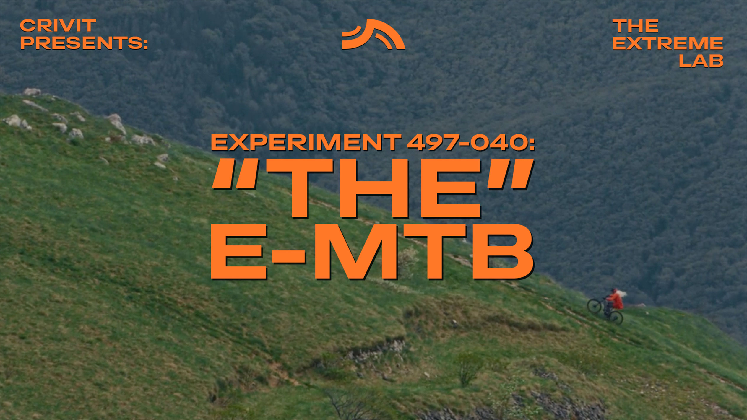 Biciklist na brdskom biciklu na travnatoj padini, s tekstom 'THE E-MTB' i 'THE EXTREME LAB'.