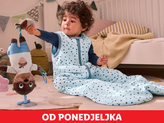 Beba u plavoj vreći za spavanje s točkicama igra se s igračkom u dječjoj sobi.
