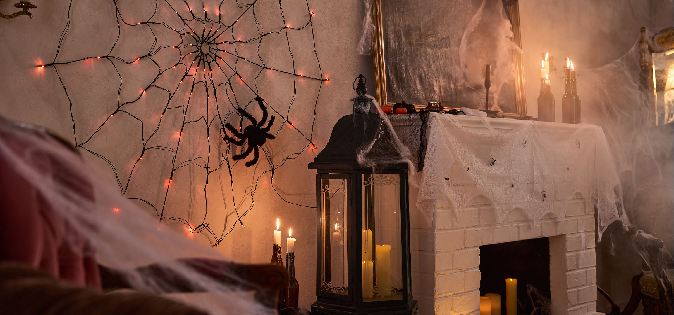 Halloween dekoracije sa svjetlima paučine, velikim paukom i svijećama.