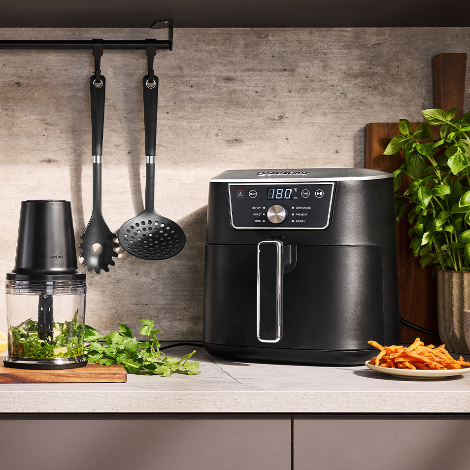 SilverCrest friteza na vrući zrak i sjeckalica za hranu na kuhinjskom pultu sa svježim začinskim biljem i pomfritom od batata.