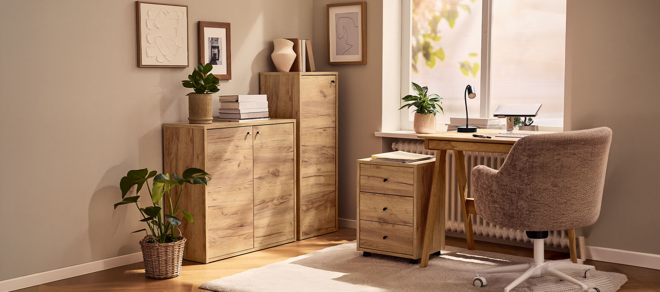 Kućni ured s drvenim ormarićima, radnim stolom i stolicom, ukrašen biljkama i slikama.