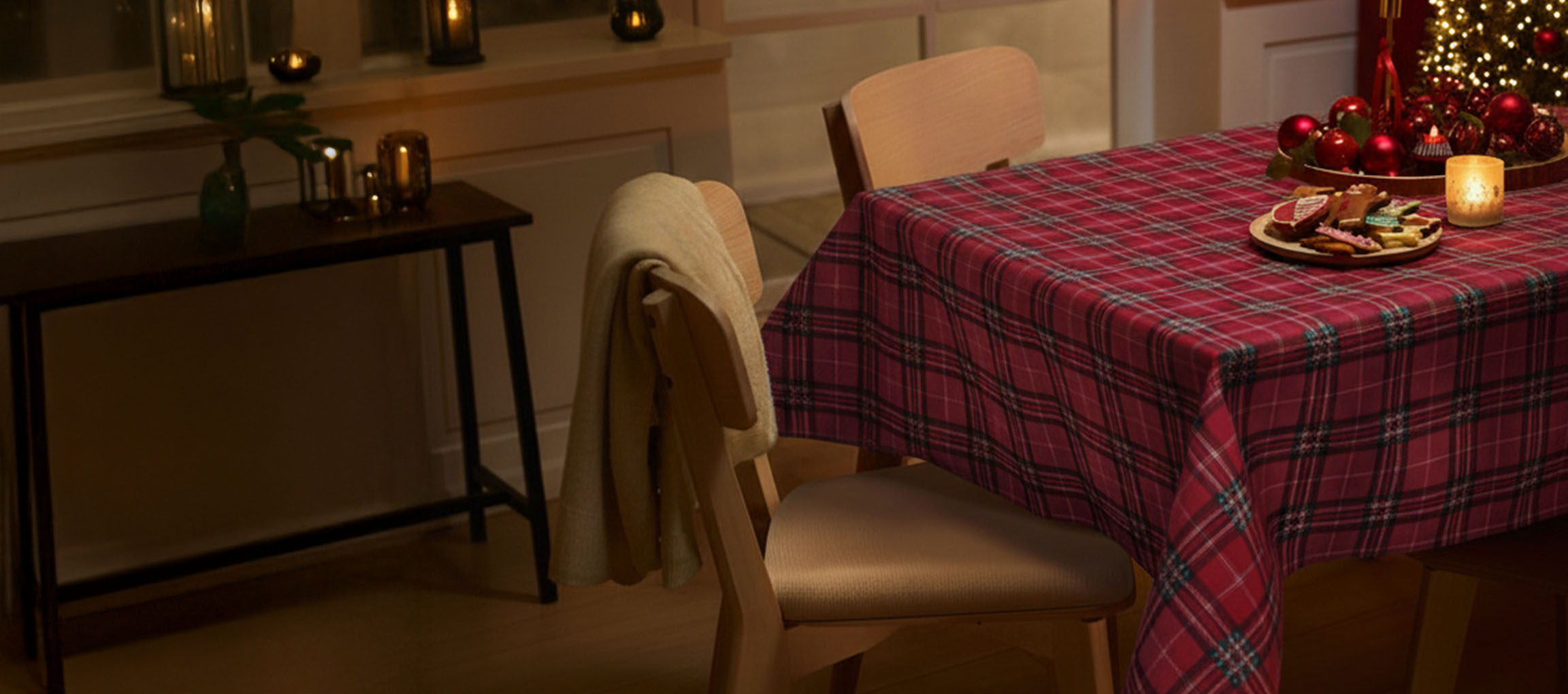 Božićni stol s crvenim kariranim stolnjakom, stolicama i božićnim kolačićima.