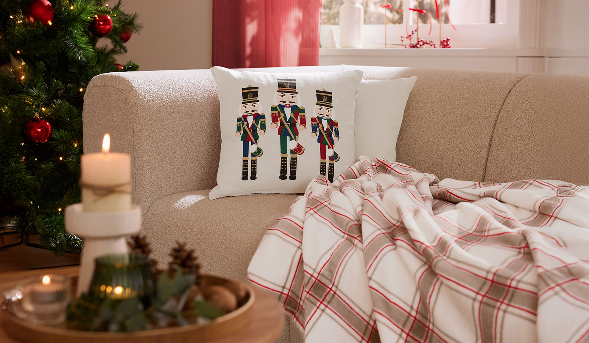 Božićni dnevni boravak s kaučem, jastucima s orašarima, kariranom dekom i svijećama.