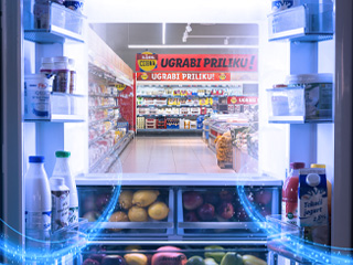 Hladnjak s mlijekom, jogurtima i voćem, koji gleda u Lidl supermarket.