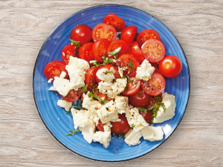 Salata od rajčica i mozzarelle na plavom tanjuru.