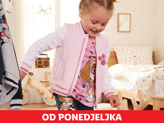 Djevojčica u ružičastoj jakni i majici s motivom Paw Patrola, s odjećom u pozadini.