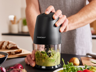 Muškarac koristi crni mini sjeckalicu SteamCrisp za pripremu guacamolea.