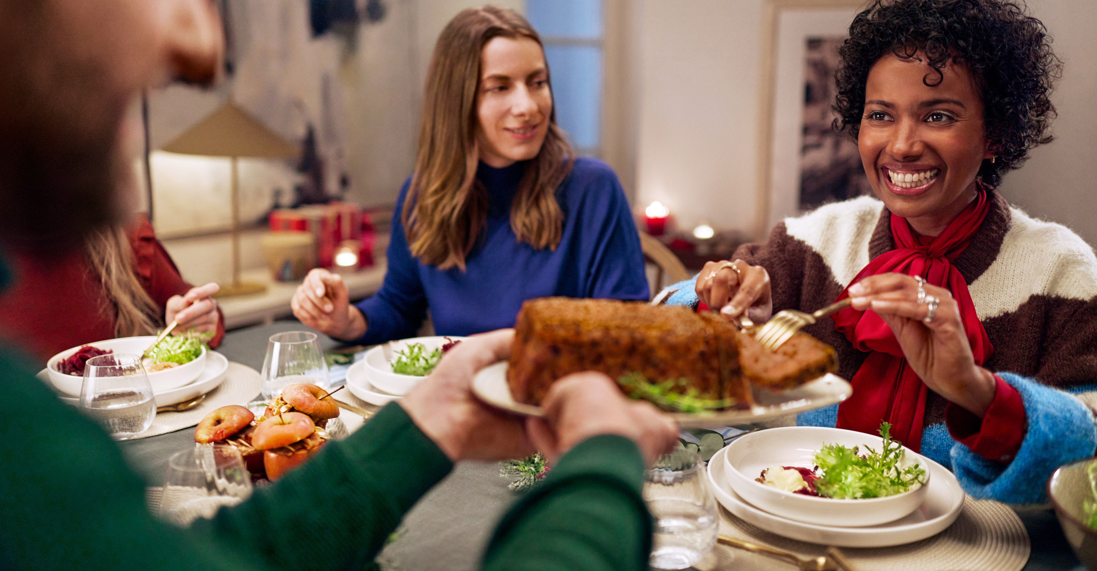 Prijatelji uživaju u blagdanskoj večeri s pečenjem i salatama.