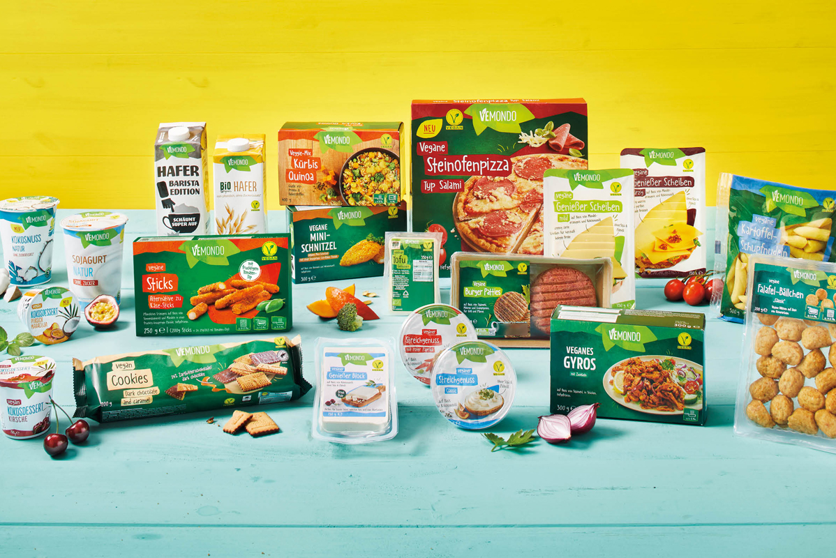 Asortiman veganskih proizvoda VEMOND, uključujući pizzu, burgere, jogurte, kekse i biljne napitke.